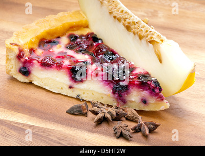 Käsekuchen mit Beeren und eine frische Melone auf einem Holztablett Stockfoto