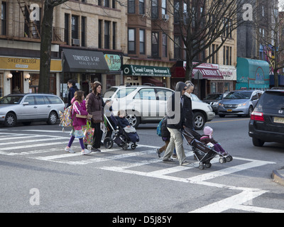 Eltern ihre Kinder Fuß zur Schule entlang 7th Ave. Drücken Sie jüngeren im Kinderwagen in Park Slope, Brooklyn, NY Stockfoto