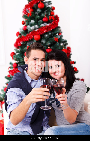 Junge Brautpaar genießen Momente der Feier mit Wein, klirrende Gläser vor x-mas tree Stockfoto