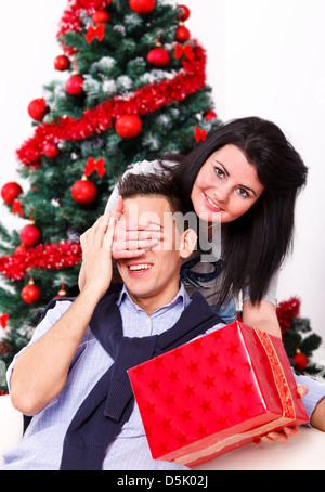 Porträt eines Mädchens ihres Freundes Augen bedecken, überraschen ihn mit einem Geschenk in der Weihnachtszeit Stockfoto