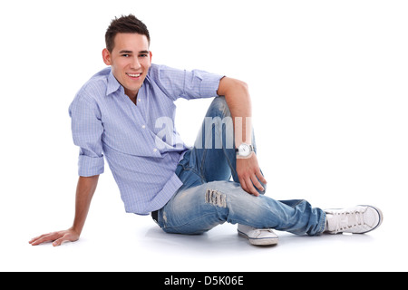 Lächelnd jungen Mann entspannend auf der Etage, Blick auf die Kamera auf weißem Hintergrund Stockfoto