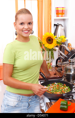 Lächelnde junge Frau macht gesundes Essen in der Küche Stockfoto
