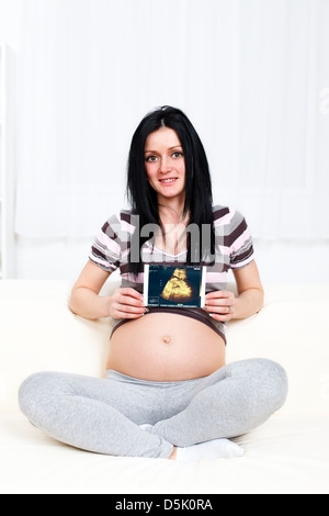 Schöne schwangere Frau zeigt ihr Baby am Ultraschall Foto Stockfoto