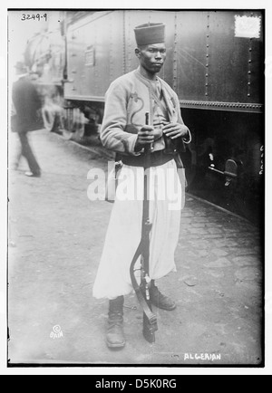 Auf diesem Foto ist ein algerischer Soldat während des Ersten Weltkriegs dargestellt, der mit einem Gewehr steht und ein fès trägt. Dieses Bild ist Teil der Library of Congress-Sammlung und zeigt die Uniform und Ausrüstung, die Soldaten während des Ersten Weltkriegs trugen. Stockfoto