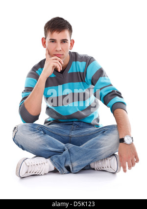 Porträt eines jungen Mannes in Jeans auf dem Boden sitzen mit gekreuzten Beinen isoliert auf weißem Hintergrund Stockfoto