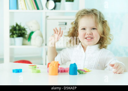 Lockige Cutie Spaß spielen mit Lehm im Kindergarten Stockfoto