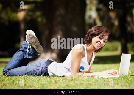 Junge Frau am Rasen im Park liegen und mit laptop Stockfoto