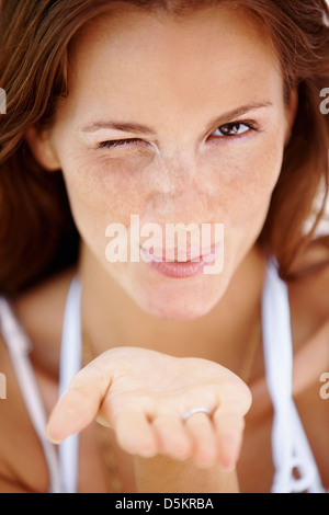 Frau zwinkert und weht einen Kuss Stockfoto