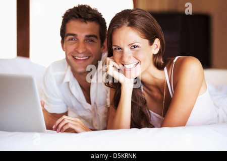 Paar mit Laptop beim liegen im Bett Stockfoto