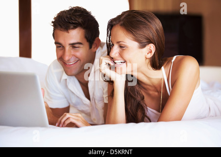 Paar mit Laptop beim liegen im Bett Stockfoto