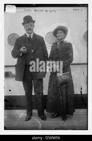 Dieses Foto zeigt Clyve Bayley und seine Frau in einem Porträt in voller Länge. Clyve trägt einen Bowler-Hut und seine Frau hält eine Tasche und einen Regenschirm, die von der Library of Congress genommen wurden. Stockfoto