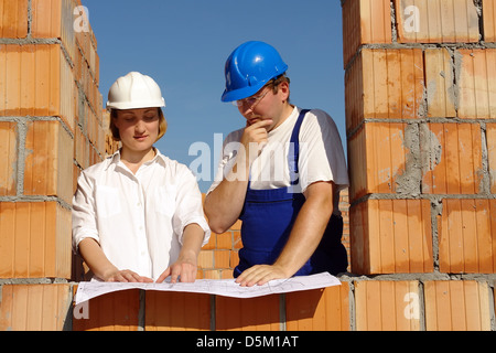Weibliche Investor und Bauleiter Baupläne unfertige Haus diskutieren Stockfoto