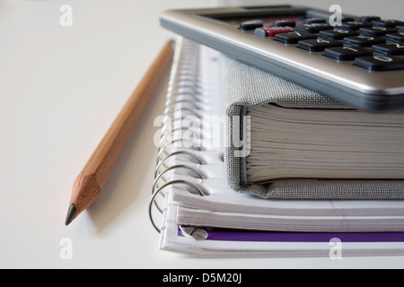 Taschenrechner, Lehrbuch und Bleistift auf Notebook, Studio gedreht Stockfoto