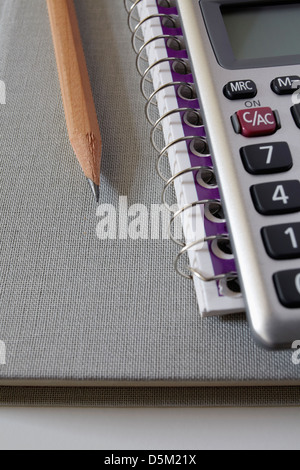 Taschenrechner, Lehrbuch und Bleistift auf Notebook, Studio gedreht Stockfoto