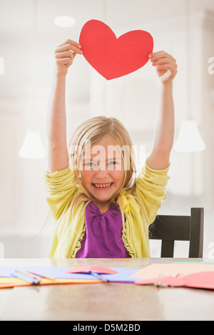 Mädchen (6-7) hält rotes Papierherz Stockfoto