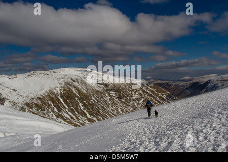 Frau Wandern mit Hund in voller winterlichen Bedingungen in The Langdales, englischen Lake District in Richtung Bowfell von rosset Hecht, Großbritannien Stockfoto