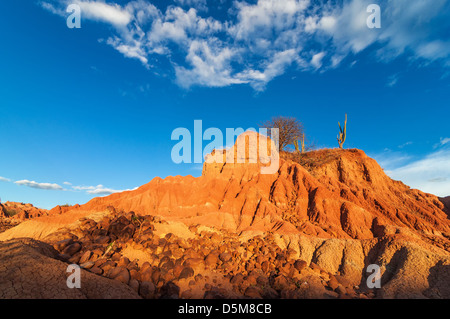 Roter Hügel in einer Wüste mit großen Felsen verstreut rund um die Basis in Huila, Kolumbien Stockfoto