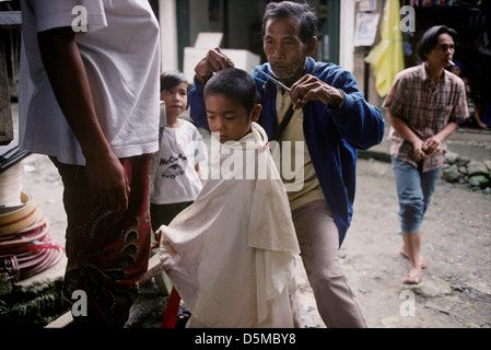 Straße Friseur einen Haarschnitt zu geben, wie Kinder aussehen auf. Mount Apo, Mindanao. Die Philippinen. Stockfoto