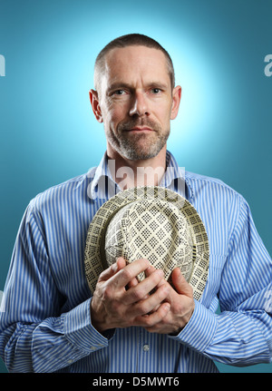 Porträt von einem reifen Erwachsenen halten eine Fedora und mit einem sanften Lächeln in die Kamera schaut. Stockfoto