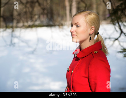 Junge Frau im roten Mantel Nachdenken über etwas Stockfoto