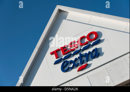 Detail von einem Tesco extra Gebäude Dach mit Zeichen und Logos Huntingdon UK vor blauem Himmel Stockfoto