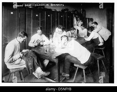 Dieses Schwarzweiß-Foto zeigt Soldaten der deutschen Armee in ihren Kasernen während der 1910er Jahre, die verschiedene Aktivitäten wie das Ausbessern von Uniformen und Kartenspielen begangen haben. Das Bild spiegelt den militärischen Alltag in Deutschland vor dem Ersten Weltkrieg wider. Stockfoto