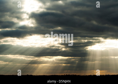 die Sonne scheint durch die dunklen Wolken. Stockfoto