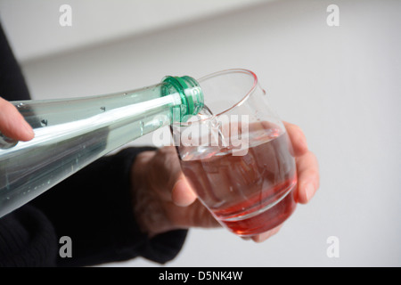 Wasser aus der Flasche in ein Glas gegossen wird Stockfoto