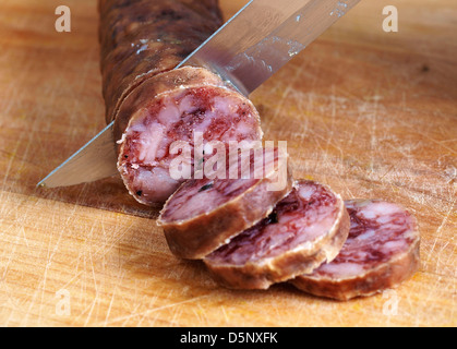 spanische Salami-Scheiben schneiden mit einem Messer Stockfoto