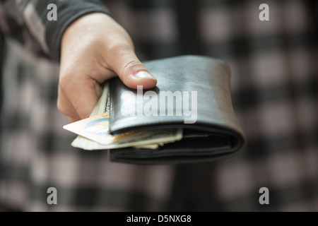 Des Mannes Hand, die eine schwarze Geldbörse mit Geld Stockfoto