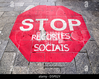 Stop-Schild auf dem Boden mit einem galizischen Sprachtext, der auf die Sozialkürzungen verweist, die in Spanien stattfinden Stockfoto
