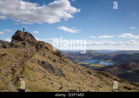 Eine Walker steht auf der Spitze Helm Crag bekannt als The Lion and The Lamb über Grasmere im Lake District National Park Cumbria Stockfoto