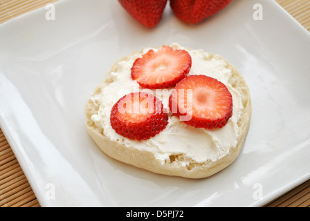 Geschnittene Erdbeeren mit Sahne-Käse auf eine englische Muffins Stockfoto