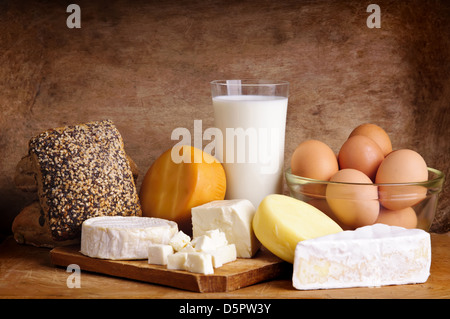 Stillleben mit Milchprodukten, Milch, Eiern, Brot und Käse auf einem Vintage Holz-Hintergrund Stockfoto