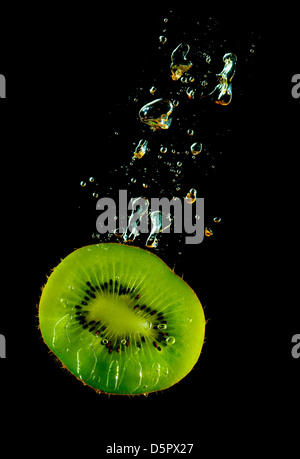 Kiwi Fruit Slice sinken im Wasser auf einem schwarzen Hintergrund Stockfoto