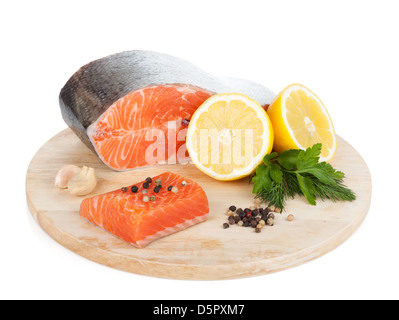 Lachs mit Kräutern und Zitronenscheiben auf Schneidebrett. Isoliert auf weißem Hintergrund Stockfoto