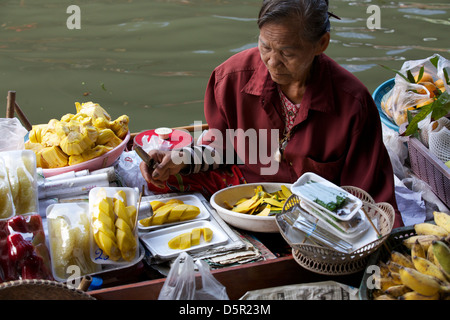 Alten Thai-Frau, Verkauf von Lebensmitteln aus ihrem Boot auf dem schwimmenden Markt in Thailand Stockfoto