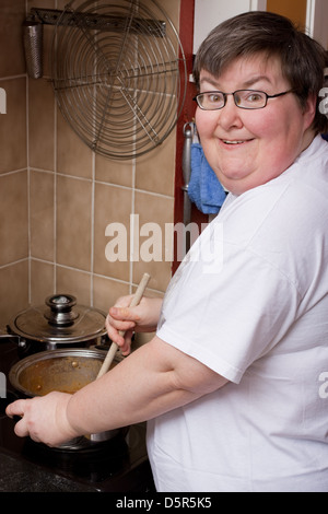 eine geistig behinderte Frau ist in der Küche kochen. Stockfoto