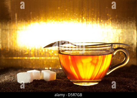 Teetasse auf getrocknete Blätter mit Löffel und Würfelzucker Stockfoto