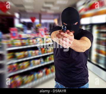 Mann in einer Maske mit einem Gewehr im Supermarkt Stockfoto