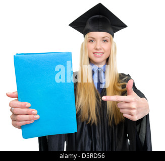 Closeup auf junge Frau in Graduierung Kleid zeigt auf Buch Stockfoto