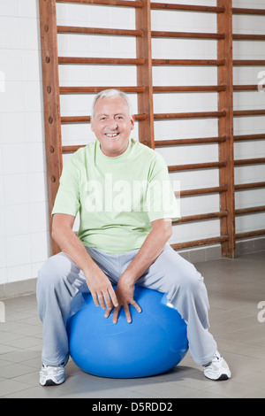 Ältere Mann sitzt auf einem Fitball Stockfoto