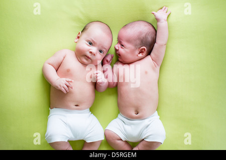 lustige Zwillinge Brüder Babys liegen auf grün Stockfoto