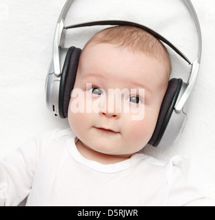 Baby mit Kopfhörer liegt auf Rücken Stockfoto