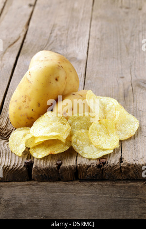 natürliche Kartoffelchips und frische Kartoffel auf einem hölzernen Hintergrund Stockfoto