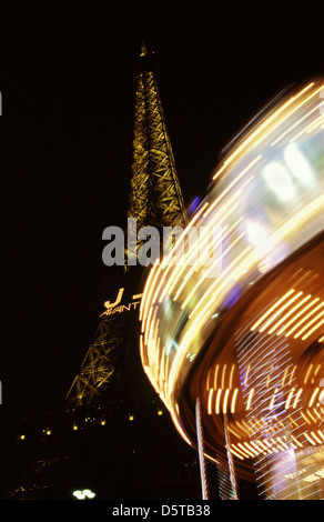 Karussell dreht rund beleuchtet in der Nacht mit Eiffelturm im Hintergrund Paris Frankreich Stockfoto