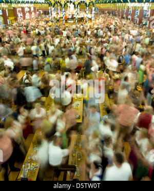 Besucher des Oktoberfestes wiegen die Musik an ihren Tischen Bier in München, Deutschland, 25. September 2012. (SECHS SEKUNDEN BELICHTUNGSZEIT). Das Oktoberfest gilt als die weltweit größte Messe und findet vom 22. September bis 7. Oktober 2012. Foto: PETER KNEFFEL Stockfoto