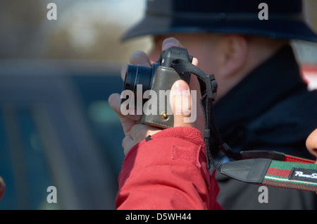 "Sightseer" mit dem Fotografieren im Zentrum von London (mit einem Polizisten im Hintergrund). Stockfoto