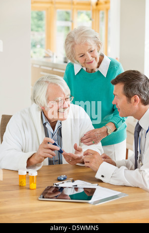 Arzt im Gespräch mit älteren Patienten und Frau Stockfoto