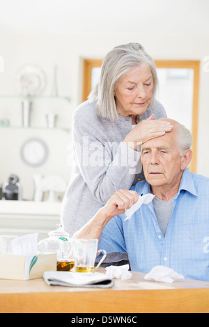 Ältere Frau Gefühl kranken Mannes Stirn Stockfoto